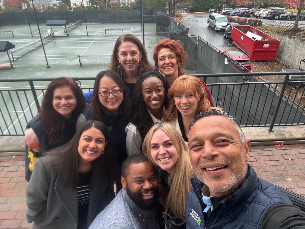 A selfie of a group of smiling men and women outdoors