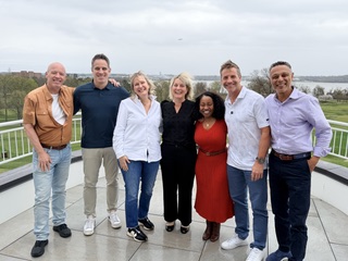 Nine smiling people posing on a balcony