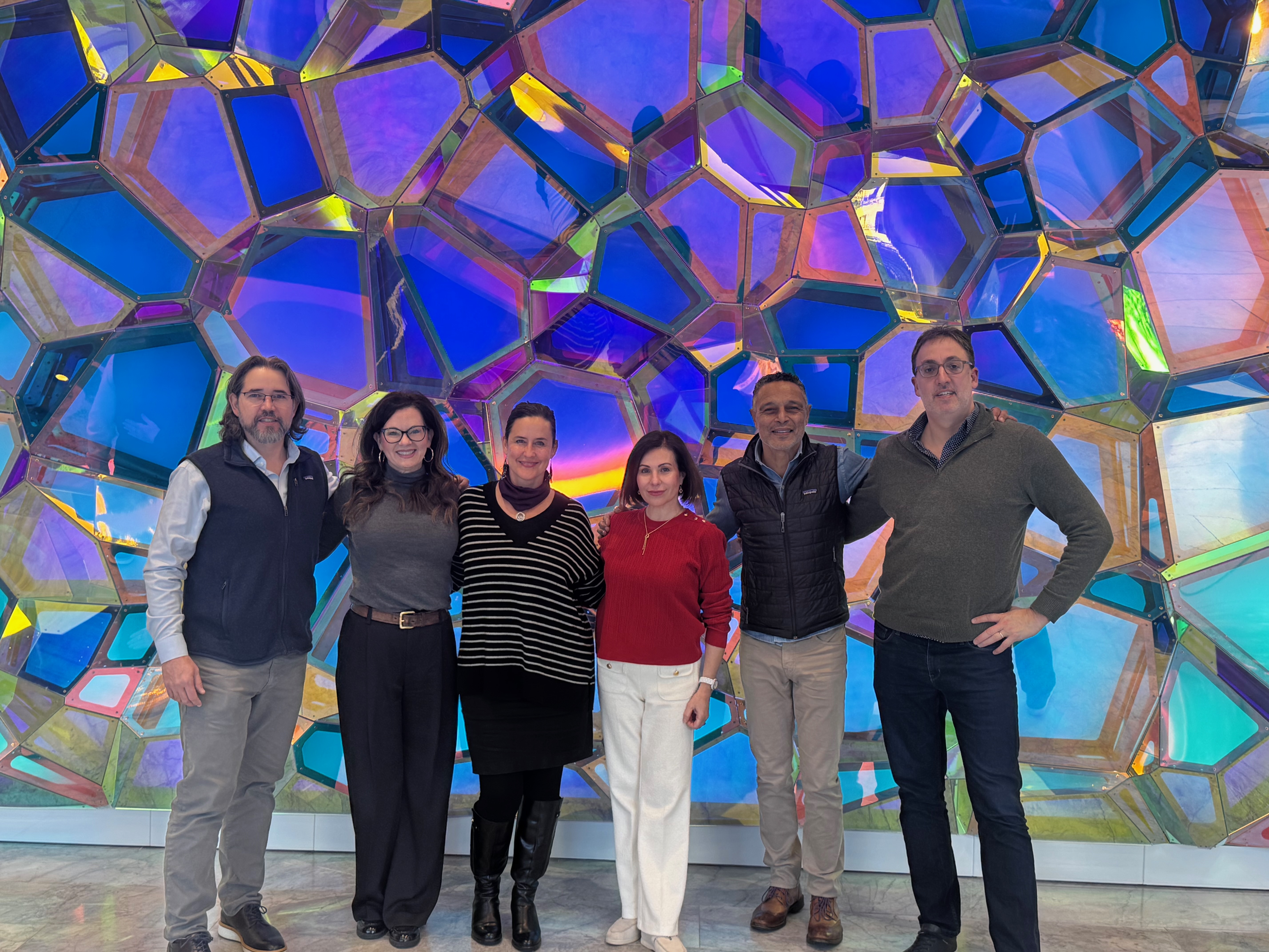 Six people in front of a light green faceted background