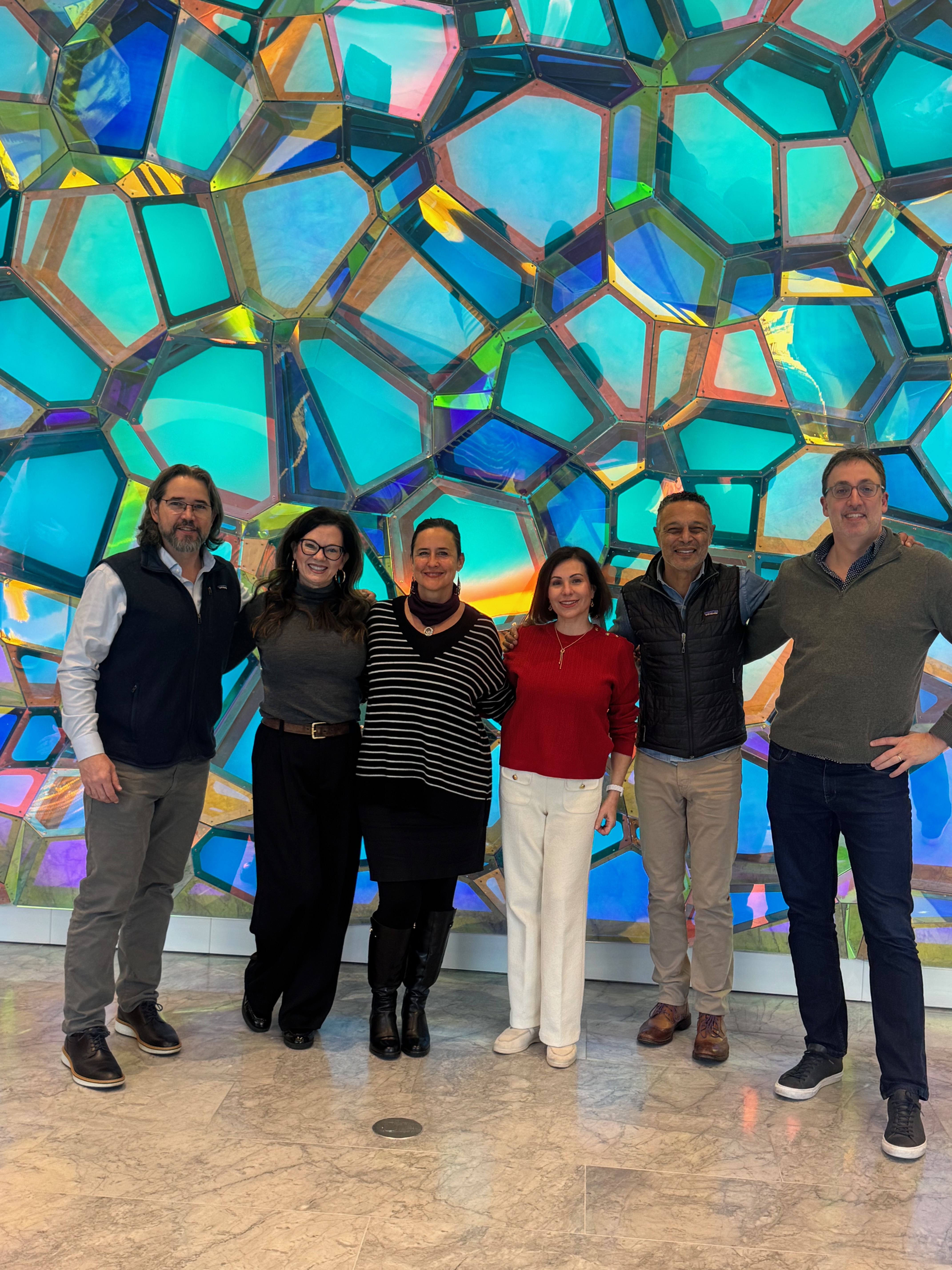 Six people in front of a purple faceted background